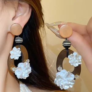 Nahaufnahme von Retro-Holzohrringen im neuen chinesischen Stil mit weißer Perlblume