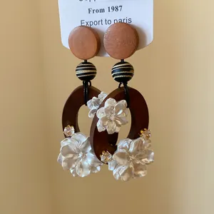 Nahaufnahme chinesischer Retro-Ohrringe mit Holzreifen und weißen Muschelblumen