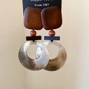 Nahaufnahme von Vintage-Ohrringen aus Holz und schimmernden Muscheln in Nischendesign