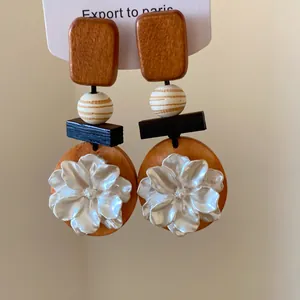 Elegante Vintage-Holzohrringe mit einem detaillierten weißen Muschelblüten-Design