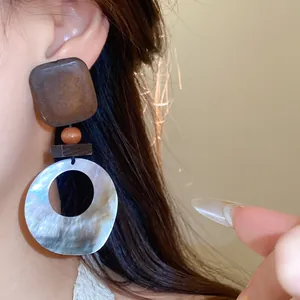 Nahaufnahme von handgefertigten Retro-Ohrringen aus Holz und Muscheln mit Textur