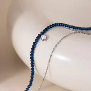 Nahaufnahme einer zweilagigen Halskette mit blauen Perlen und tropfenförmigem Zirkon
