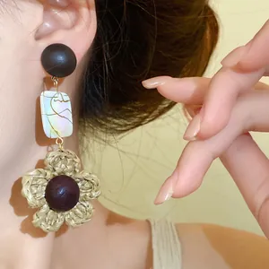 Close-up view of vintage bohemian woven flower earrings with wood bead and pearl shell details