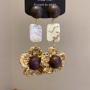 Detailed view of vintage Bohemian earrings with wood beads and woven straw flowers