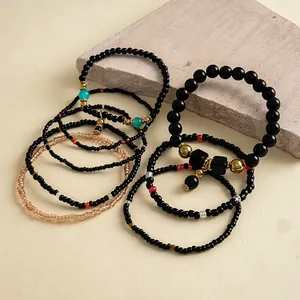 Detailweergave van een 8-delige set zwarte glazen kralenarmbanden met goud.