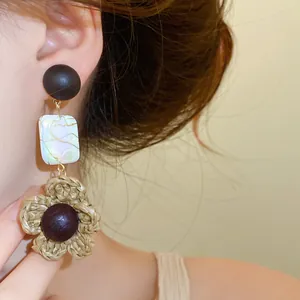 Detail view of bohemian retro earrings with wood bead and woven flower accent