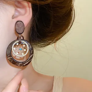 Bohemian dreamcatcher style coconut shell and wood drop earrings worn by a model