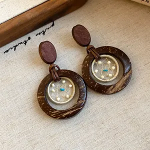 Close-up of bohemian wood and coconut shell drop earrings with beaded web design