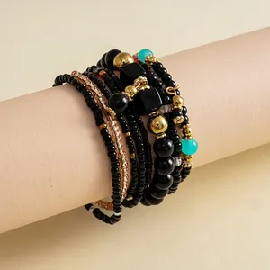 Detailopname van een 8-delige zwarte en gouden kralenarmbandset op een neutrale houder.