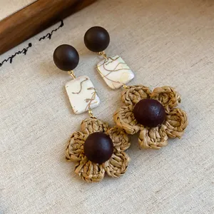 Close-up of bohemian style woven straw flower earrings with vintage dark wood beads