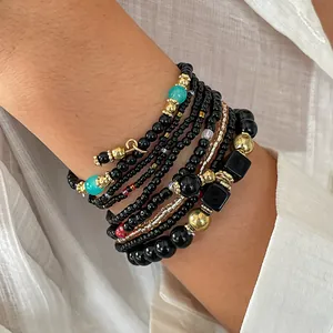 Gedetailleerde close-up van een stijlvolle achtdelige armbandset met zwarte glaskralen en goud
