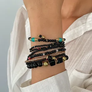 Detailweergave van een 8-delige zwarte glazen kralenarmbandset met gouden accenten
