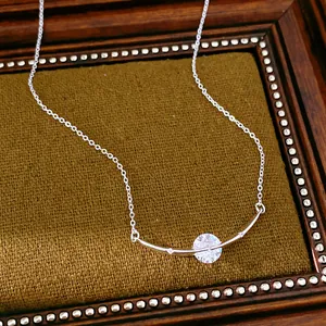 Close-up of a silver curved bar necklace with round zircon in a vintage frame