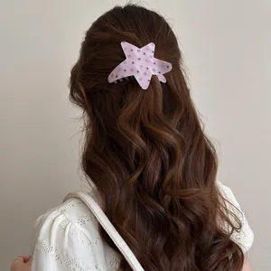 Detailed shot of a pink star-shaped acetate hair claw clip with black polka dots.