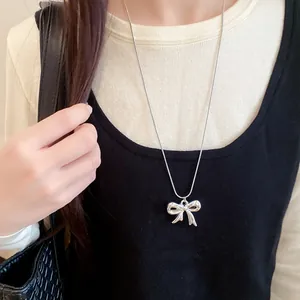 Primer plano de collar con lazo de metal plateado en modelo con estilo chic y elegante.