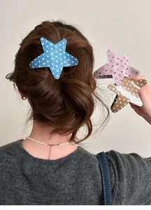 Close-up detail of cute star-shaped hair clips in blue denim, pink polka dot and tan patterns