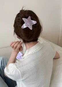 Aesthetic star-shaped acetate hair clip with polka dots shown on a model's hair for styling