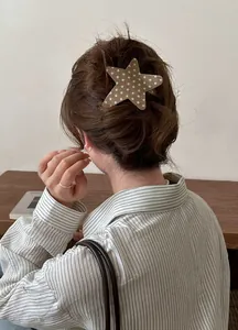 Rear view of a stylish acetate star-shaped hair clip with small white stars in brown hair