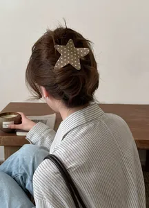 Close-up detail of a stylish star pattern acetate hair clip styled in a classic low bun