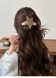 Rear view detail of a stylish star-shaped acetate hair clip on wavy brown hair.