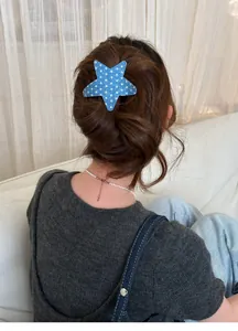 Close-up view of a stylish blue star hair clip with white stars worn on long brown hair