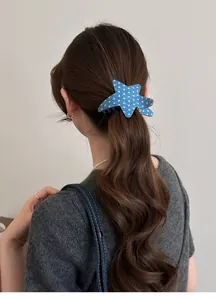 Close-up of a blue acetate star-patterned hair clip worn on a brunette ponytail.