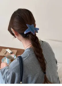 Detail showing a stylish star-shaped denim texture hair clip worn on a braided ponytail