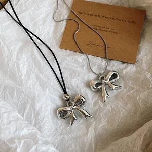 Detalle de collares con lazo metálico, cordón de cuero y cadena de serpiente plateada