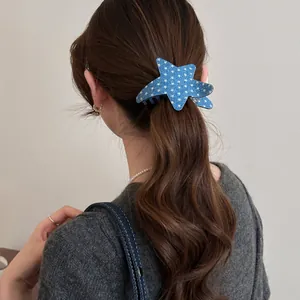 Close-up of a blue star-shaped hair claw clip with white patterns on a ponytail.