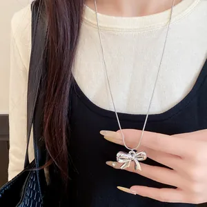 Detalle de un collar con colgante de lazo de metal plateado brillante en una modelo real