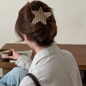 Close-up of a stylish star-shaped acetate hair clip styled on a brunette woman's messy bun