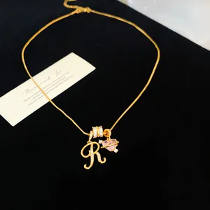 Détail d'un collier plaqué or 18 carats avec une lettre R en zircon et un cœur rose