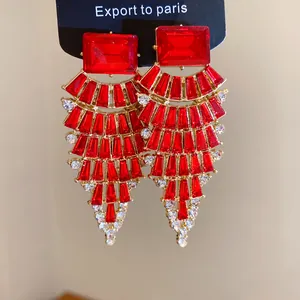 Vue détaillée de grandes boucles d'oreilles en éventail avec des cristaux rouges éclatants