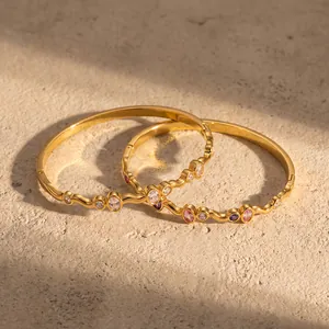 Nahaufnahme goldener Edelstahlarmreifen mit bunten ovalen Zirkonia-Steinen