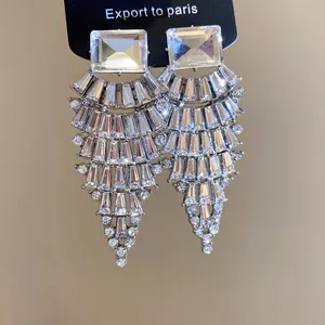 Vue détaillée de boucles d'oreilles pendantes argentées en éventail avec strass brillants.