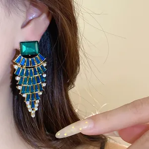 Vue rapprochée de boucles d'oreilles pendantes en forme d'éventail avec cristaux verts et bleus