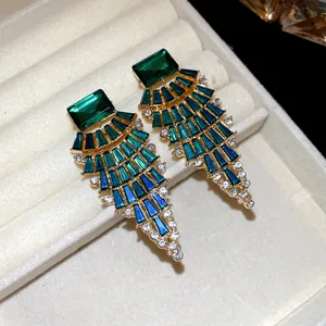 Vue détaillée des boucles d'oreilles en éventail avec cristaux vert émeraude et bleus
