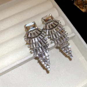 Détail rapproché de boucles d'oreilles scintillantes avec cristaux carrés et en éventail.