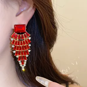 Gros plan de boucles d'oreilles glamour en forme d'éventail avec strass rouges et blancs.