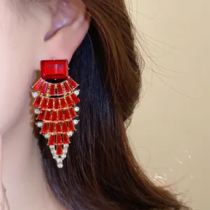 Gros plan de boucles d'oreilles en éventail rouges exagérées avec strass sur un mannequin.