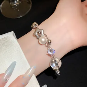 Gros plan d'un bracelet élégant avec perle et pendentif fleur porté au poignet
