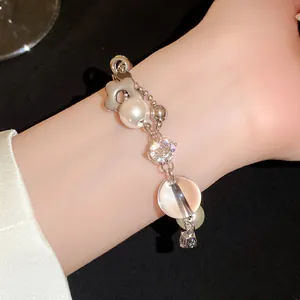 Vue détaillée d'un bracelet en argent avec zircons étincelants, perles et un pendentif fleurie.