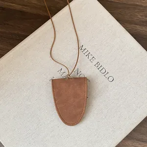 Detail of a brown triangular faux leather glasses clip necklace on a book.