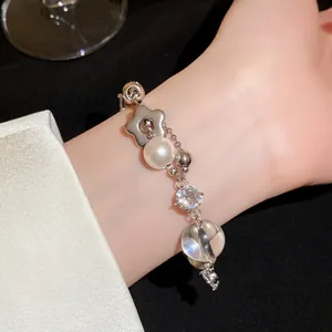 Vue détaillée d'un élégant bracelet en argent avec perles, zircons et fleurs au poignet