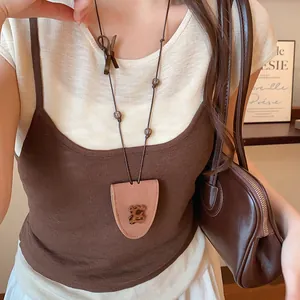 Close-up of brown leather eyeglass holder necklace with leopard heart bear charm