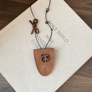 Detail view of a brown faux leather glasses holder necklace with leopard cat charm.