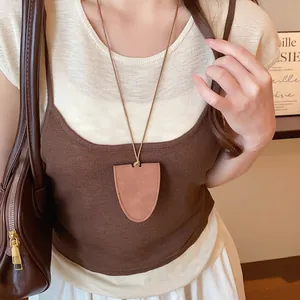 Close-up of stylish brown faux leather shield pendant necklace worn by female model