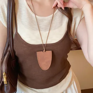 Detail view of a brown faux leather glasses holder necklace worn with a knitted top