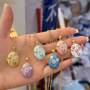 Hand holding a variety of colorful stainless steel enamel flower photo locket necklaces for women