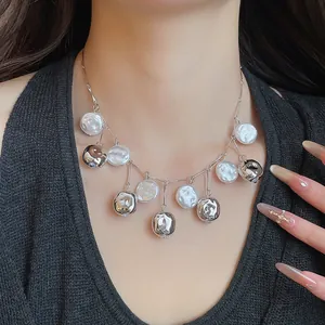 Detailaufnahme einer silbernen Quastenkette mit strukturierten Metall- und weißen Perlenanhängern